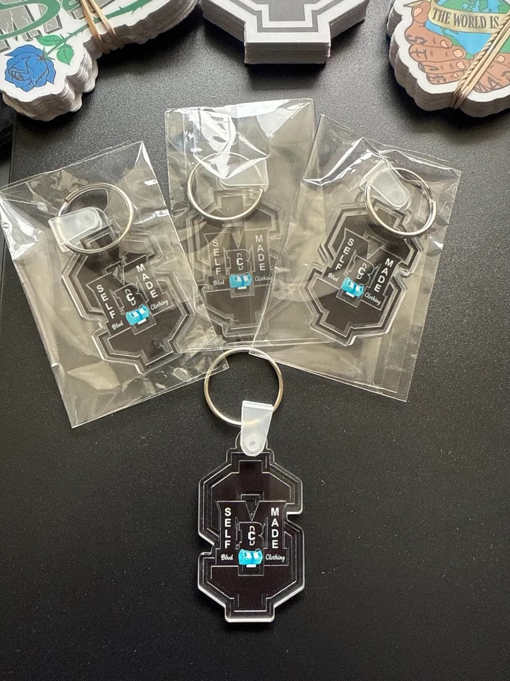 Black acrylic logo keychains, each in its own bag