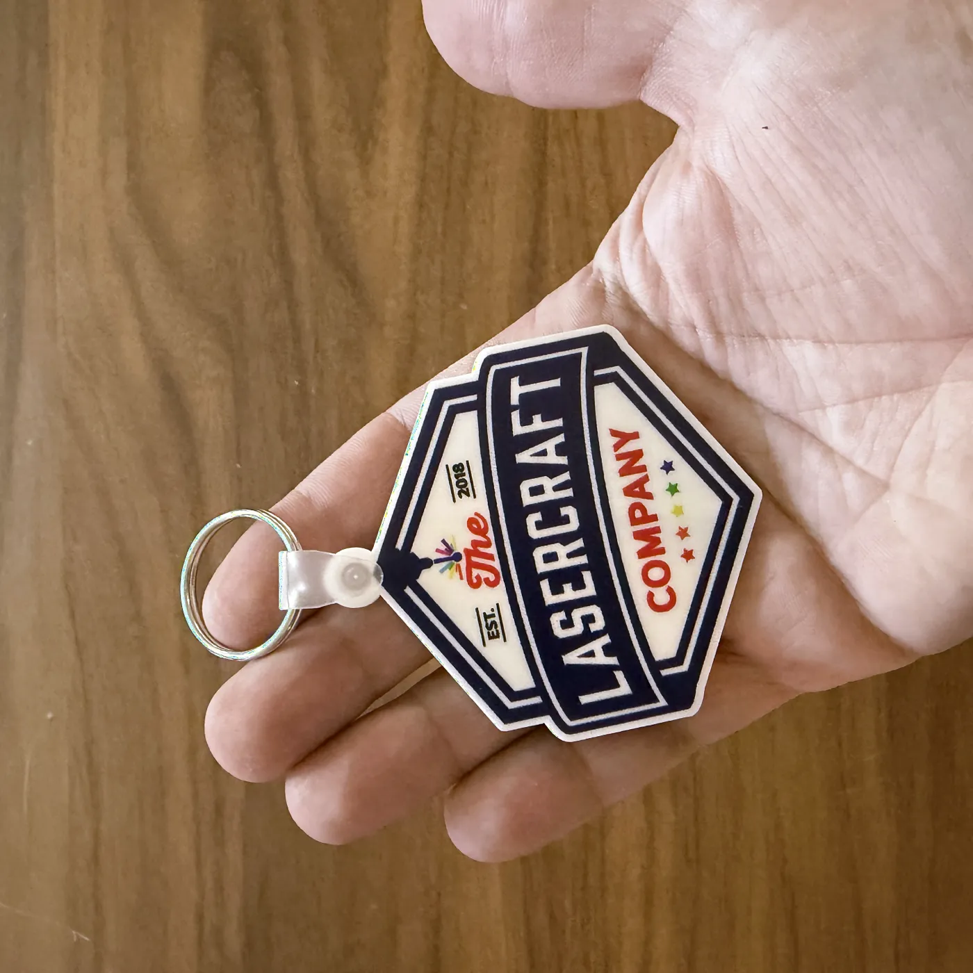 Hexagon logo keychain with a white back held in a hand